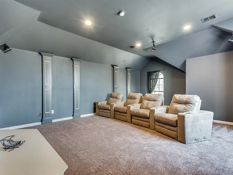 Dedicated entertainment space featuring a large projection screen, recessed lighting, and sloped ceilings