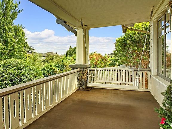 Wide, covered front-porch entry with river rock detail, and a porch swing.