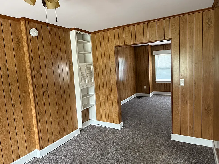 View of dining room and built-in corner shelving, with view of living room.