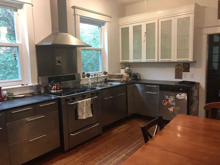 Half of the kitchen. 3 large windows looking toward side yard. Lots of light. New stove. Ample cabinets and storage.