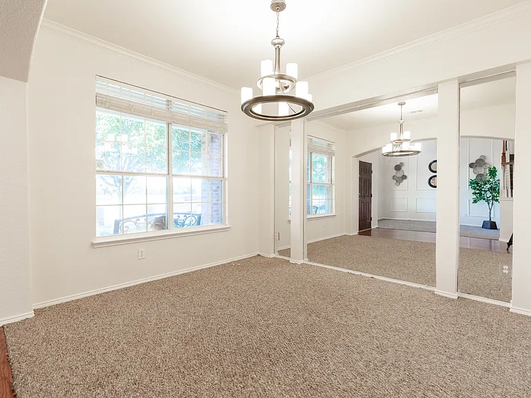 Formal dining with decorative light and mirror wall