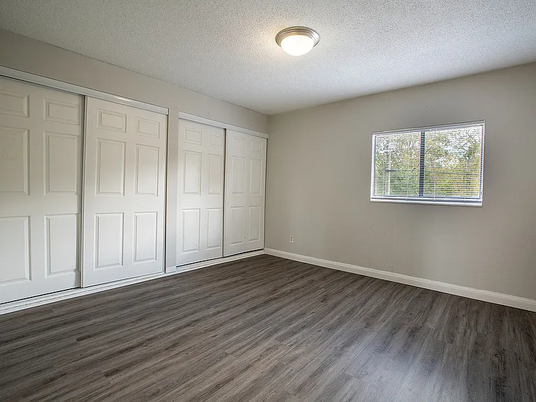Bright, spacious bedroom with sleek hardwood flooring and ample closet space, perfect for stylish living.