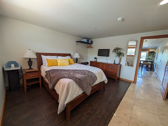 Large bedroom with queen sized bed, smart TV, large dresser, and blackout blinds.