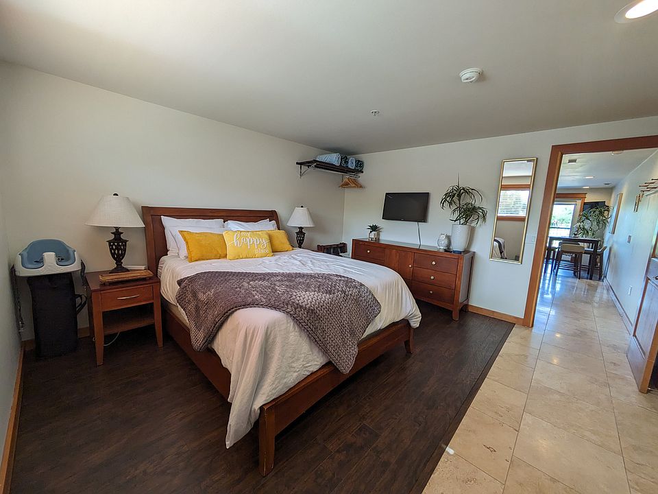 Large bedroom with queen sized bed, smart TV, large dresser, and blackout blinds.