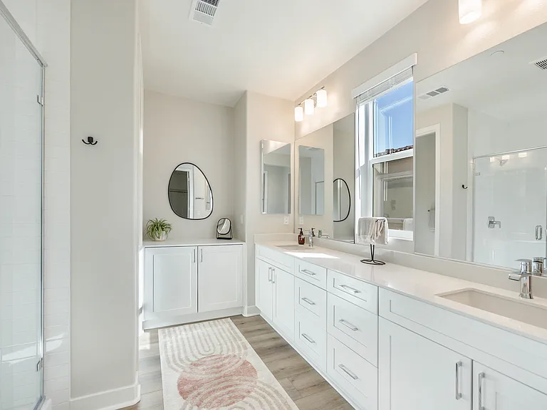 The master suite features a large step-in tile shower, his and hers vanity sinks, and a private restroom.
