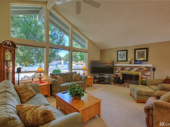 Large living room with ceiling fan and wood fireplace.