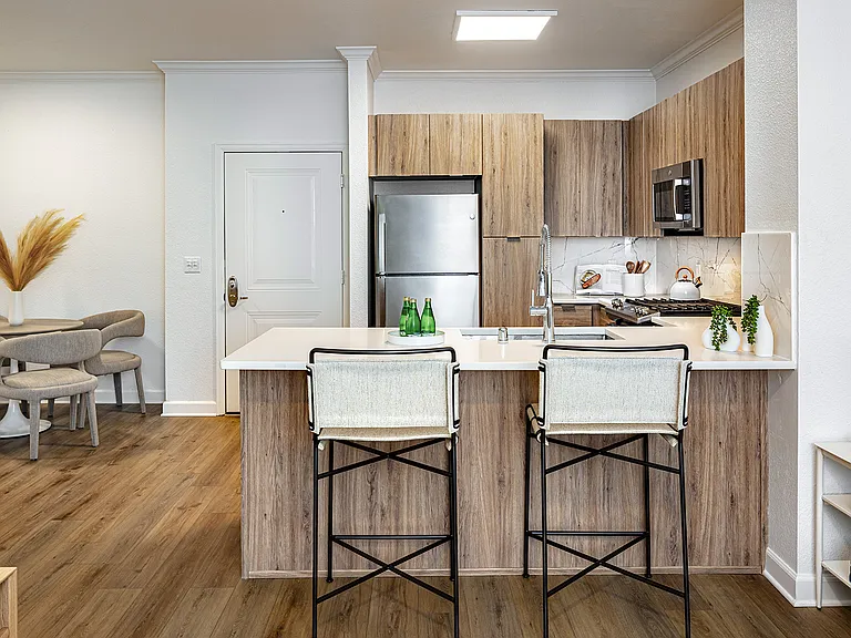 A kitchen with a breakfast bar and a view of the adjacent dining area with a round table.