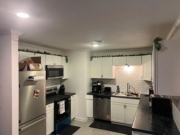 U-shaped kitchen with white cabinets, subway-tile backsplash, ample counters, and stainless appliances including dishwasher.