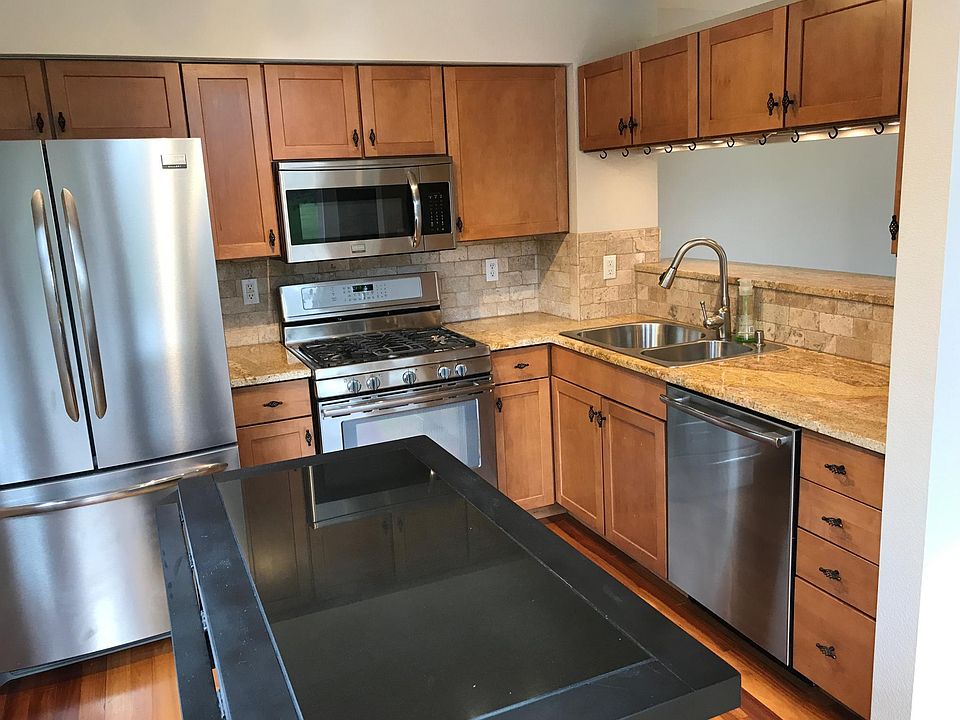 Light-filled updated kitchen with stainless steel appliances including a french door refrigerator, granite counter tops, mood lighting, chef's island and pan rack.