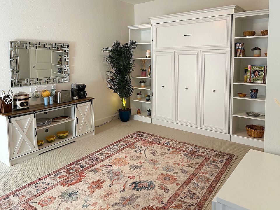 White paneled murphy bed, pulls down to a comfortable queen sized bed. Kitchenette to the left