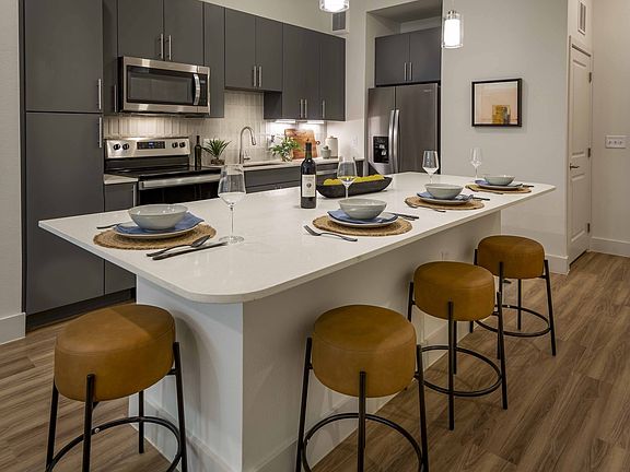Indulge in culinary delights within Modera Garden Oaks' gourmet kitchens, highlighted by quartz countertops and custom 42-inch cabinetry featuring under-cabinet lighting for both style and practicality.