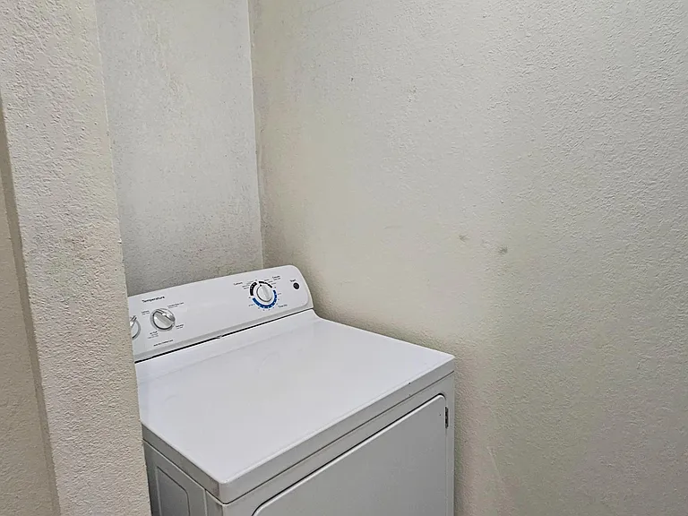 Compact laundry nook with an in-unit dryer and tile flooring, offering convenient on-site laundry access.