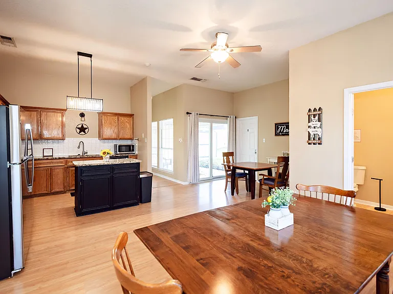 Open-concept kitchen and dining area with island seating, ample cabinetry, and sliding doors to the backyard patio.