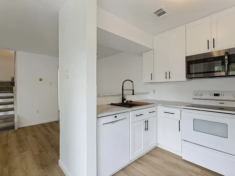 Kitchen featuring white shaker-style cabinetry, a stainless steel microwave, white range, and a dishwasher