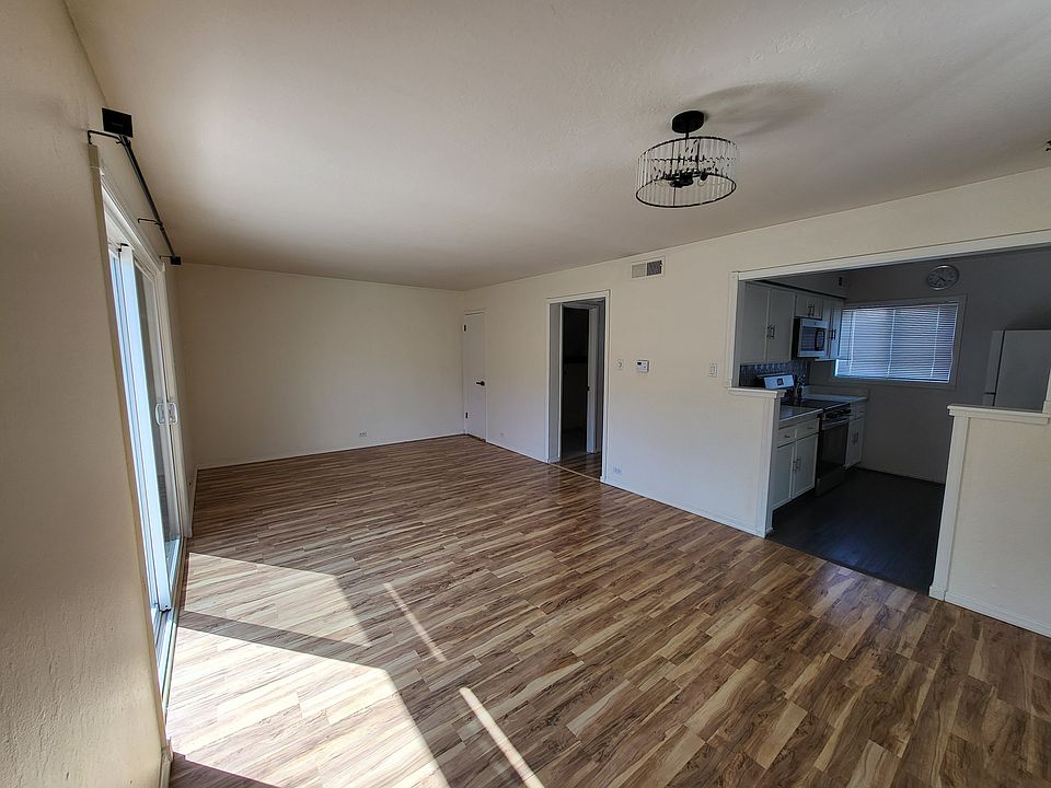 Spacious open-concept living and dining area featuring elegant laminate flooring and a stylish chandelier. Dual-pane windows throughout the home provide energy efficiency, natural light, and year-round comfort.