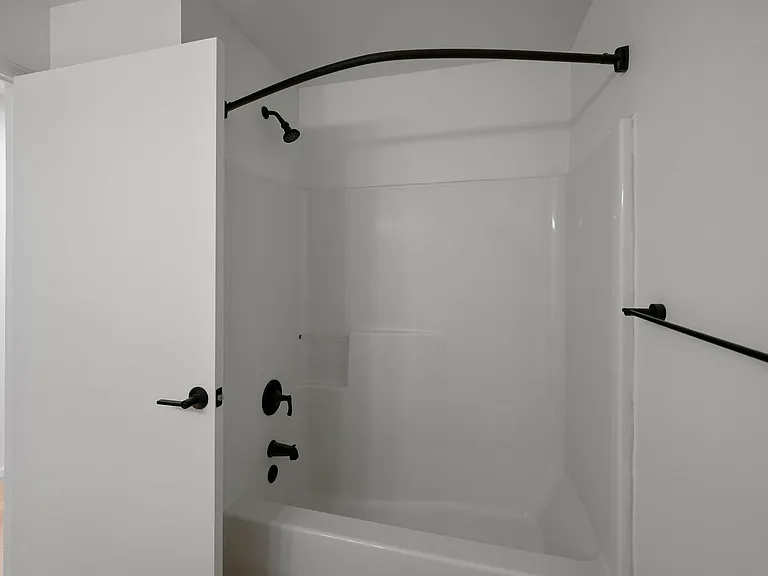 Modern bathroom with a pristine white bathtub and matte black fixtures.