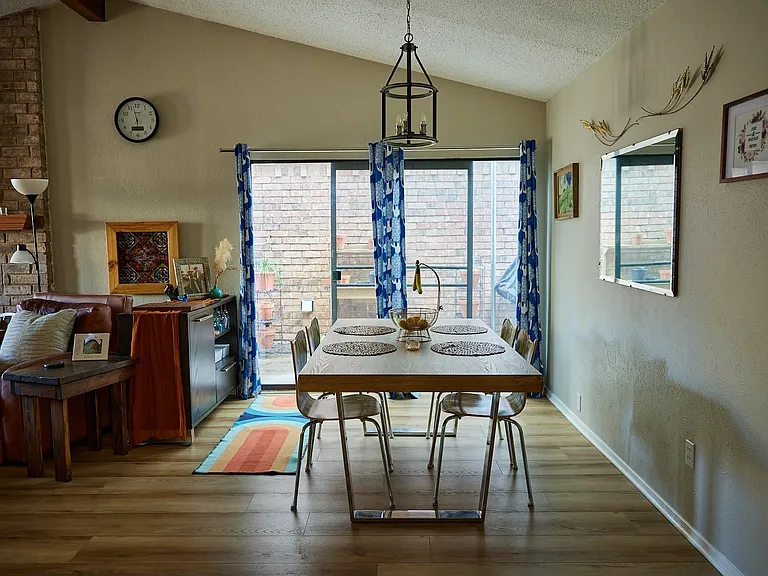 Dining area featuring lofted ceiling, light wood finished floors, a textured ceiling, and a brick fireplace