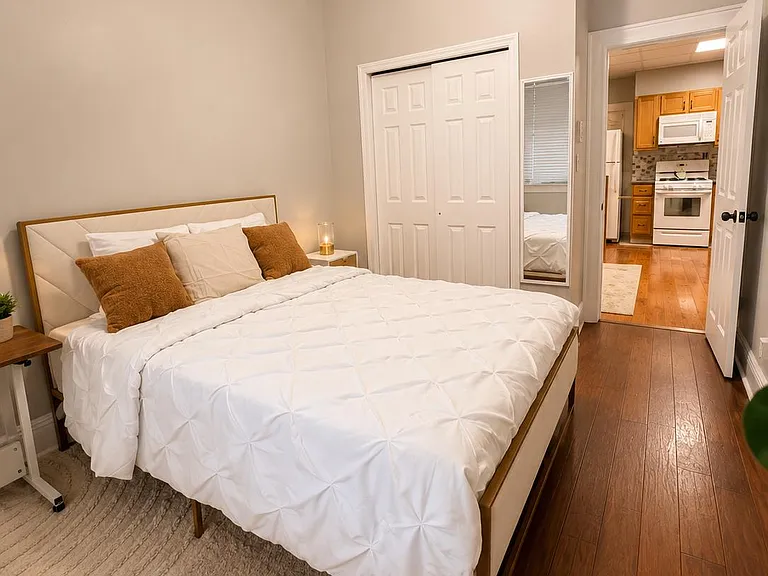 Well-appointed bedroom with a queen bed, hardwood floors, and a closet, plus easy access to the kitchen area.