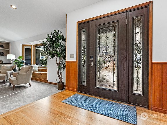 Newer leaded glass front door leads to the foyer with vaulted ceiling, Edison bulb chandelier and bead board wainscoting.>