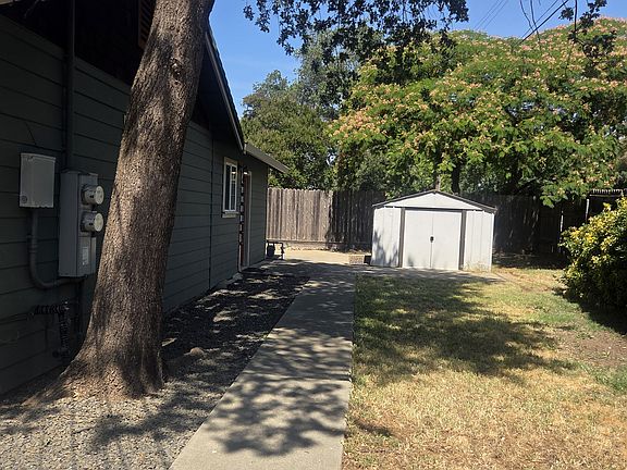 Fenced sideyard with shed. Sidewalk leads to 2nd entry and around to back patio