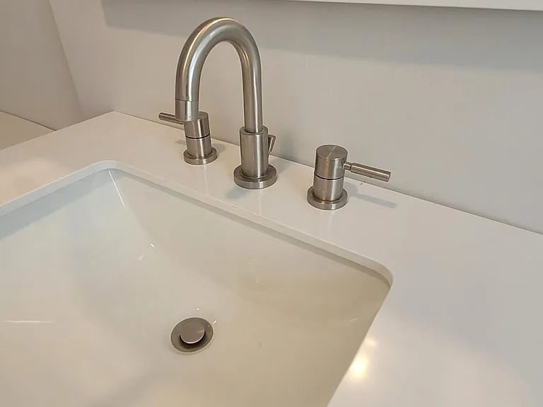 Stone, wide rimmed sink countertop with brushed nickel faucet