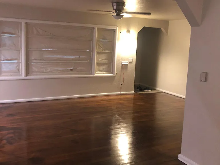 Large living room , with huge window, new stainless steel ceiling fan and refinished wood floor.