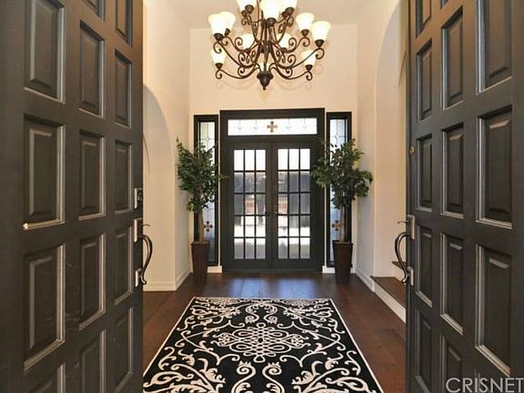 Front entrance looking into stunning foyer with Spanish details. Doors lead to garage.