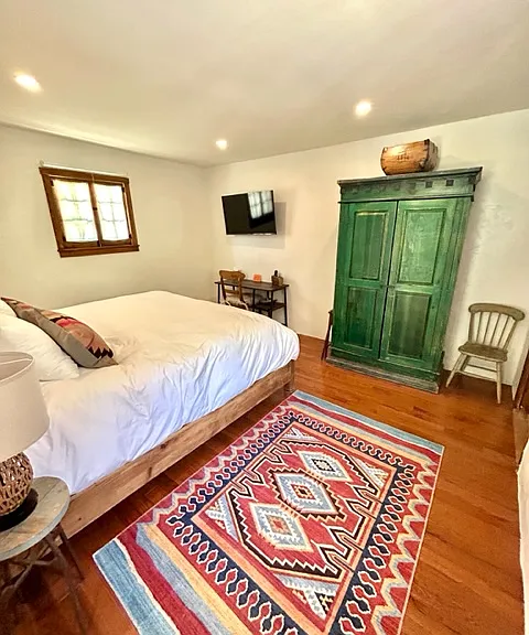 Casita bedroom: king-size hand-carved bed with hybrid mattress and luxury linens, vintage armoire (dresser upon request), 42" smart TV and desk.