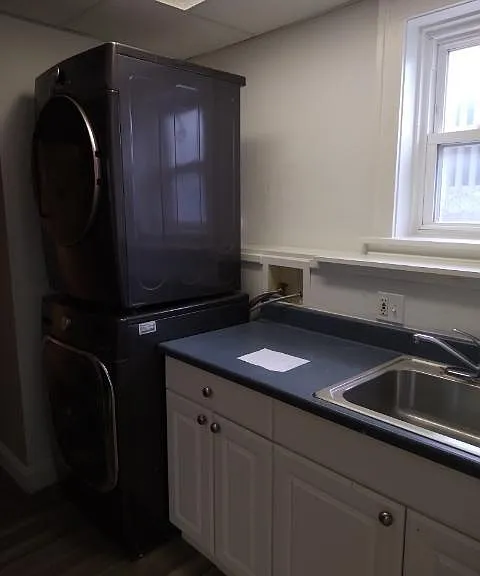 Kitchen area with full size washer and dryer, sink, oven with stove top and refrigerator.
