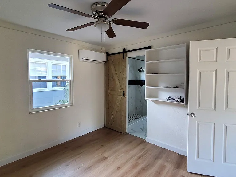 Bedroom 1 showing sliding barn door to the bathroom. Closet is behind the door to living room.