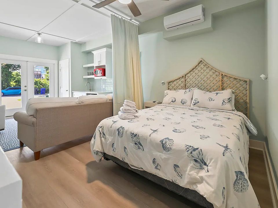 Queen Bed with nightstand, privacy drape, overhead light/fan, and heat/cool air unit.