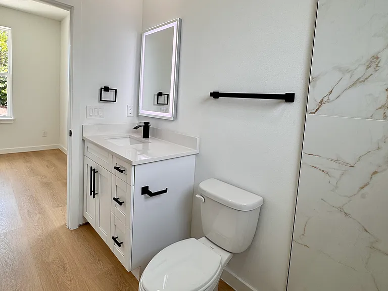 Sleek bathroom with walk-in shower and LED vanity mirror.