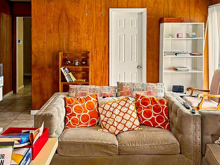 Common living area with ceiling fan, tile flooring, and comfortable seating, plus shelving for books and shared storage.