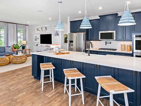 Open kitchen with blue cabinets, white counters and adjacent morning room in a DRB Homes St. Kitts M
