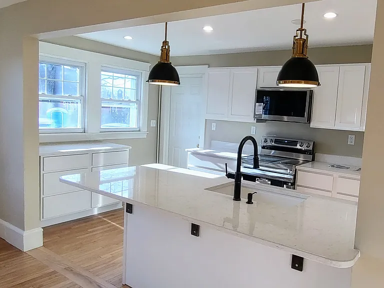 A renovated kitchen with marble countertops, spacious storage and a large island.