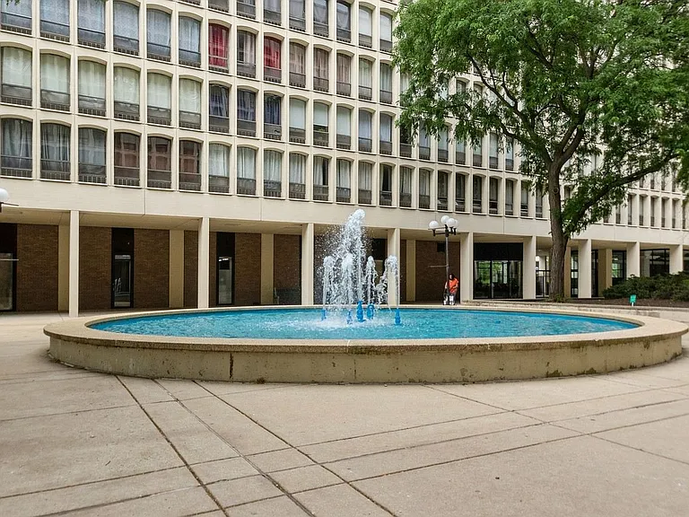 Large outdoor patio with fountain, between the two buildings with security fencing enclosing it all.