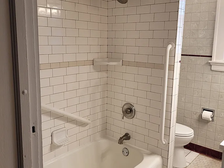 First floor bathroom with new subway tile around tub with hand rails