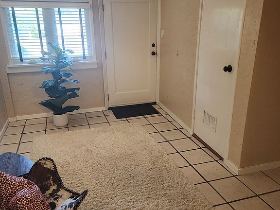 View of living room from kitchen, and showing the bedroom door and the front door.