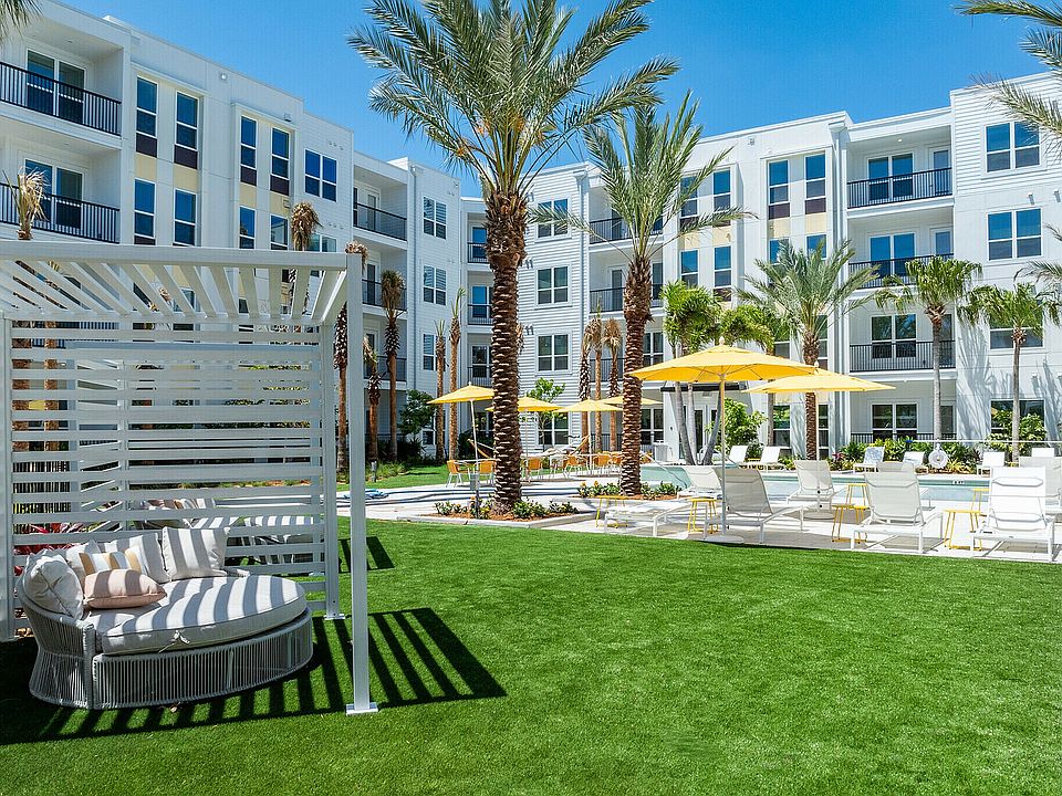 Luxurious apartment exterior with sunny poolside, palm trees, and stylish cabana seating.