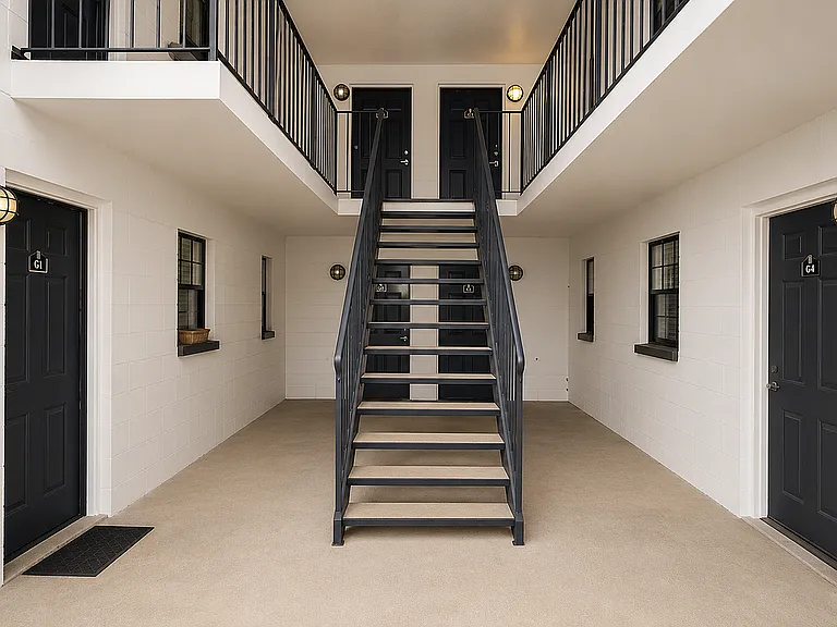 Modern apartment entry with sleek black doors, elegant stairway, and contemporary lighting.