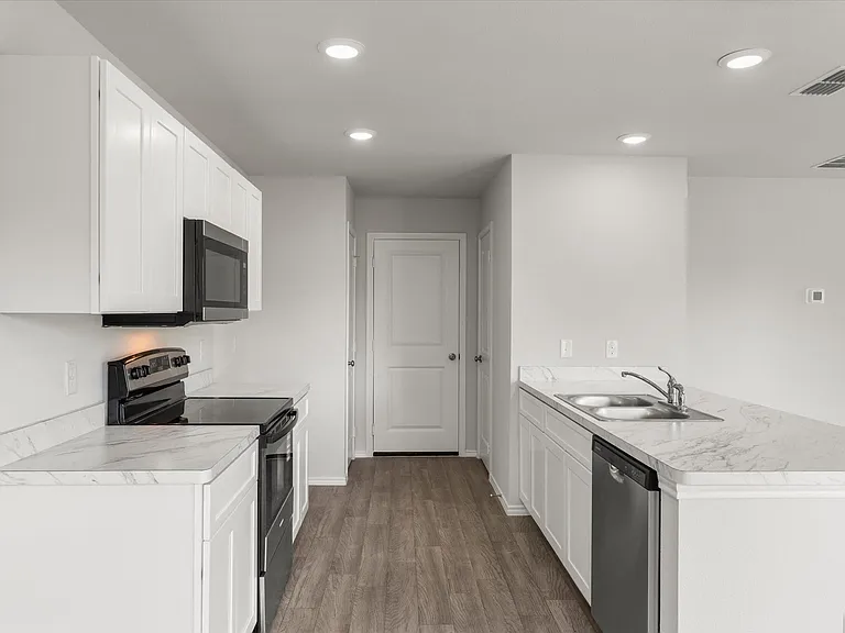 Modern kitchen featuring white cabinetry, stone-finish countertops, stainless steel appliances, a double basin sink, and wood-finish flooring