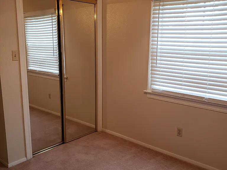Second bedroom showing mirror closet doors and fan.