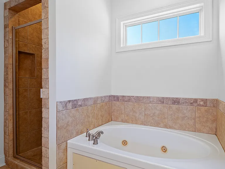 The primary bath has a soaking tub and walk-in tile shower.