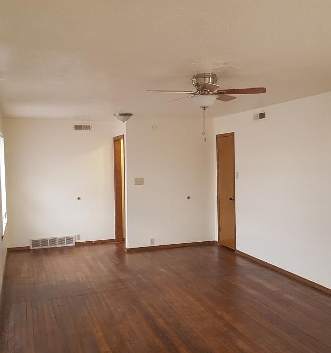Large living room with hardwood flooring and ceiling fans