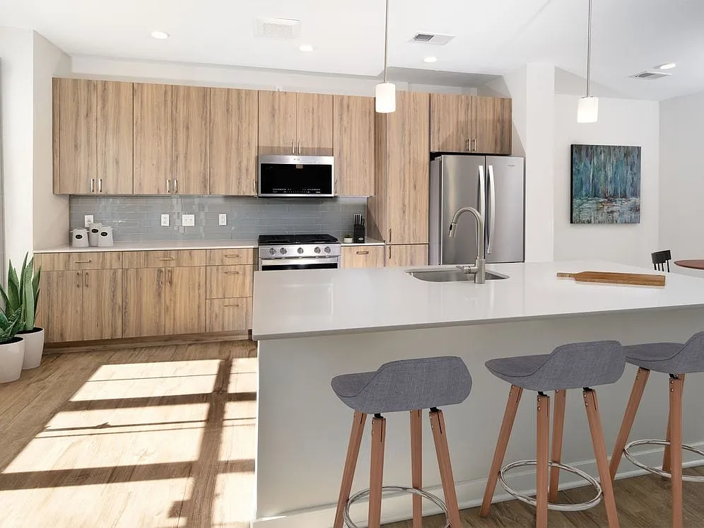 Upgrade Scheme townhome kitchen and dining areas with oak cabinetry, grey tile backsplash, grey quartz countertops, stainless steel appliances, and hard surface flooring - Avalon Old Bridge