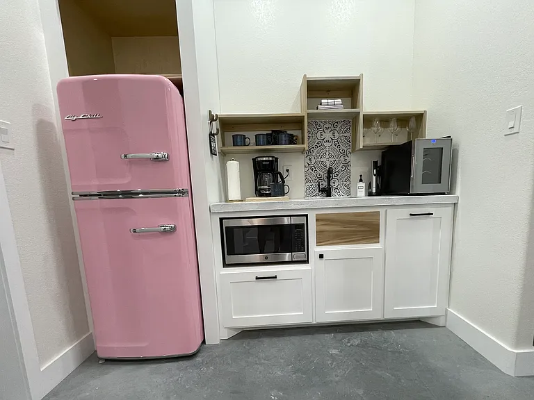 Galley kitchen includes: refrigerator, wine cooler, microwave, and coffee maker.