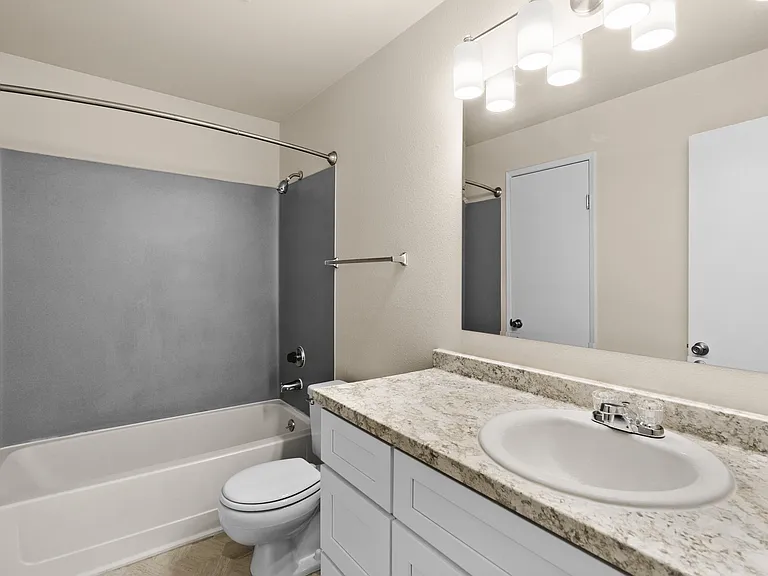 Modern bathroom with elegant granite countertop, spacious mirror, and contemporary lighting. Modern bathroom with elegant granite countertop, spacious mirror, and contemporary lighting.
