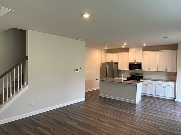 Kitchen island with undermount sink, dishwasher, and breakfast bar overlooking the living area