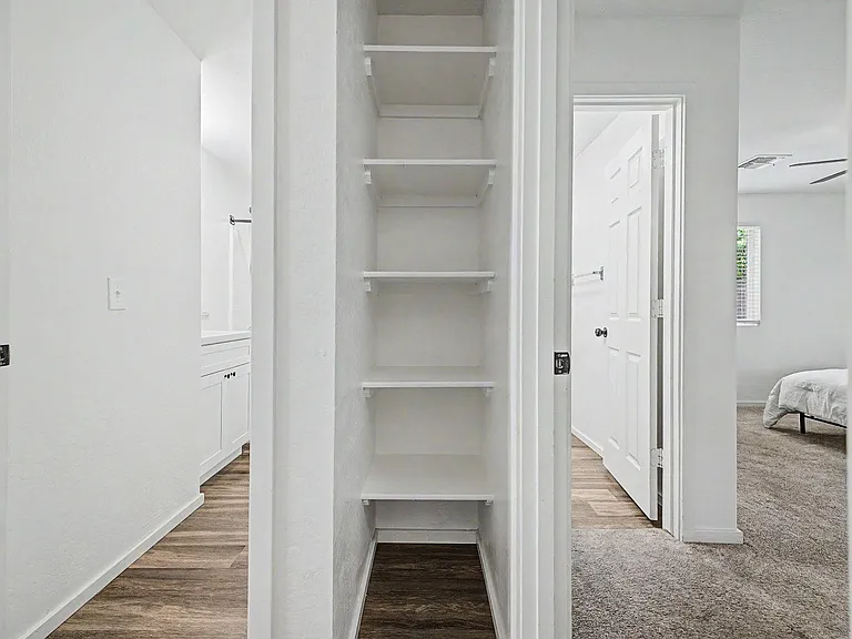 Hallway storage nook features built-in shelving for pantry or linen organization, with easy access to nearby bedroom and bath
