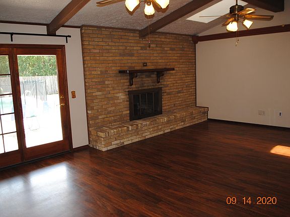 Living room with pool view, skylight, and wood burning fireplace.